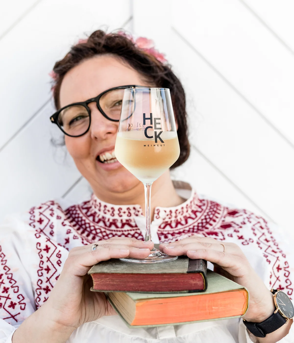 Lotte Heck mit HECK-Glas und einem Bücherstapel